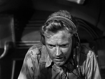 Movie still from “Air Force” (1943), directed by Howard Hawks – A man with headphones on looking down at the ground; Close Up shot, High angle