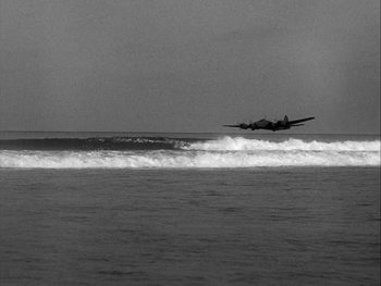Movie still from “Air Force” (1943), directed by Howard Hawks – An airplane is flying low over the water; Extreme Wide shot, Low angle