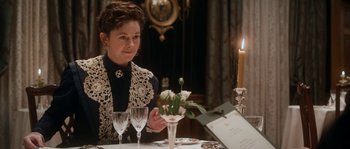 Movie still from “Albert Nobbs” (2011), directed by Rodrigo García – A woman sitting at a table with a glass of wine; Medium shot, Over the shoulder angle