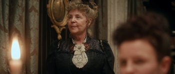 Movie still from “Albert Nobbs” (2011), directed by Rodrigo García – An older woman wearing a black dress and a black hat; Close Up shot, Over the shoulder angle