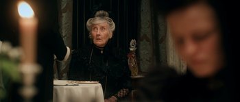 Movie still from “Albert Nobbs” (2011), directed by Rodrigo García – An older woman sitting at a table in front of a table; Medium shot, Over the shoulder angle