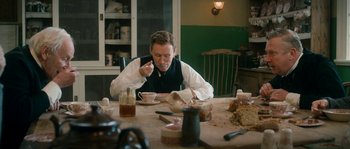 Movie still from “Albert Nobbs” (2011), directed by Rodrigo García – A man sitting at a table with a plate of food in front of him; Medium shot, Over the shoulder angle