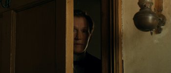 Movie still from “Albert Nobbs” (2011), directed by Rodrigo García – A man looking out of a window in a dark room; Close Up shot, Low angle