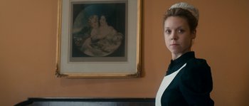 Movie still from “Albert Nobbs” (2011), directed by Rodrigo García – A woman standing in front of a painting in a living room; Medium shot, Low angle