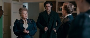 Movie still from “Albert Nobbs” (2011), directed by Rodrigo García – A man and two women standing next to each other in a room; Medium shot, Over the shoulder angle