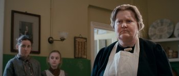 Movie still from “Albert Nobbs” (2011), directed by Rodrigo García – A woman wearing a white apron standing next to a girl; Close Up shot, Over the shoulder angle