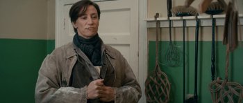 Movie still from “Albert Nobbs” (2011), directed by Rodrigo García – A woman standing next to a door wearing a scarf; Medium shot, Over the shoulder angle