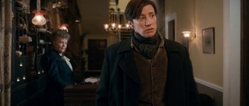 Movie still from “Albert Nobbs” (2011), directed by Rodrigo García – A woman in a black coat and a brown scarf; Medium shot, Over the shoulder angle