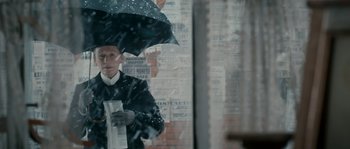 Movie still from “Albert Nobbs” (2011), directed by Rodrigo García – A man holding an umbrella while standing in the rain; Medium shot, Over the shoulder angle