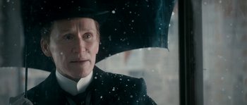 Movie still from “Albert Nobbs” (2011), directed by Rodrigo García – An older man in a suit and tie holding an umbrella; Close Up shot, Over the shoulder angle