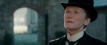 Movie still from “Albert Nobbs” (2011), directed by Rodrigo García – An older man wearing a suit and a hat; Close Up shot, Over the shoulder angle