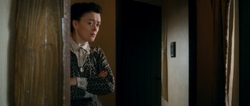 Movie still from “Albert Nobbs” (2011), directed by Rodrigo García – A woman standing with her arms crossed in front of a door; Medium shot, Over the shoulder angle