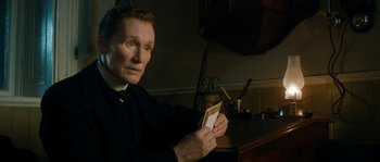 Movie still from “Albert Nobbs” (2011), directed by Rodrigo García – A man in a priest's outfit holding a card; Close Up shot, Low angle