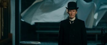 Movie still from “Albert Nobbs” (2011), directed by Rodrigo García – A man wearing a top hat standing in front of an umbrella; Medium shot, Low angle