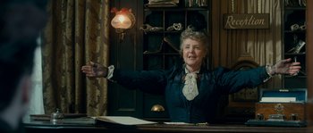Movie still from “Albert Nobbs” (2011), directed by Rodrigo García – An older woman sitting at a desk in front of a book case; Medium shot, Low angle