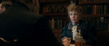 Movie still from “Albert Nobbs” (2011), directed by Rodrigo García – An older woman sitting at a table with a glass of wine; Close Up shot, Over the shoulder angle