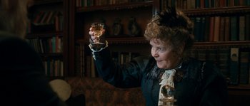 Movie still from “Albert Nobbs” (2011), directed by Rodrigo García – An older woman holding a glass of wine in her right hand; Medium shot, Low angle
