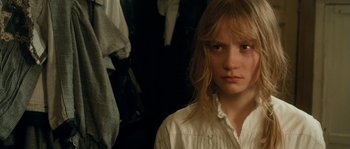 Movie still from “Albert Nobbs” (2011), directed by Rodrigo García – A young girl in a white shirt is standing in front of some clothes; Close Up shot, High angle