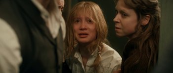Movie still from “Albert Nobbs” (2011), directed by Rodrigo García – A woman with long blonde hair is crying in front of two other people; Close Up shot, Over the shoulder angle