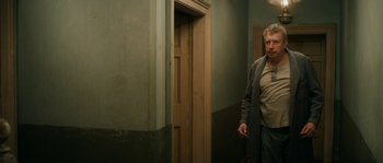 Movie still from “Albert Nobbs” (2011), directed by Rodrigo García – A man walking in a hallway next to an open door; Medium shot, Over the shoulder angle