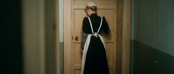 Movie still from “Albert Nobbs” (2011), directed by Rodrigo García – A woman dressed as a maid opening a door; Medium shot, High angle