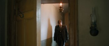 Movie still from “Albert Nobbs” (2011), directed by Rodrigo García – A man wearing a suit and tie walking down a hallway; Wide shot, Over the shoulder angle