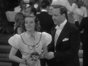 Movie still from “Alice Adams” (1935), directed by George Stevens – A man and a woman in formal wear standing next to each other; Medium shot, Low angle