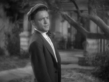 Movie still from “Alice Adams” (1935), directed by George Stevens – A man wearing a suit and a hat standing in front of a tree; Close Up shot, High angle