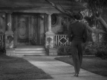 Movie still from “Alice Adams” (1935), directed by George Stevens – A woman walking down a sidewalk in front of a house; Wide shot, High angle
