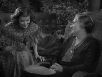 Movie still from “Alice Adams” (1935), directed by George Stevens – Two women are sitting on a bench and one of them is holding an umbrella; Medium shot, High angle