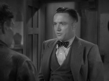 Movie still from “Alice Adams” (1935), directed by George Stevens – A black and white photo of a man wearing a suit and bow tie; Close Up shot, Over the shoulder angle