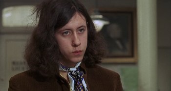 Movie still from “Alice's Restaurant” (1969), directed by Arthur Penn – A man with long hair wearing a brown jacket and a tie; Close Up shot, Low angle