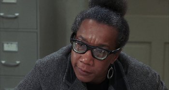 Movie still from “Alice's Restaurant” (1969), directed by Arthur Penn – An older woman wearing glasses and a jacket; Close Up shot, Over the shoulder angle