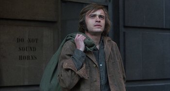 Movie still from “Alice's Restaurant” (1969), directed by Arthur Penn – A man holding his jacket over his shoulder; Medium shot, Low angle