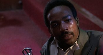 Movie still from “Alice's Restaurant” (1969), directed by Arthur Penn – A person wearing a suit and tie; Close Up shot, Low angle