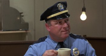 Movie still from “Alice's Restaurant” (1969), directed by Arthur Penn – A police officer holding a coffee cup in his hand; Close Up shot, Over the shoulder angle
