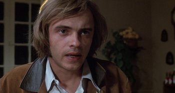 Movie still from “Alice's Restaurant” (1969), directed by Arthur Penn – A man with long blonde hair wearing a brown jacket; Close Up shot, Low angle