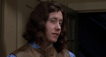 Movie still from “Alice's Restaurant” (1969), directed by Arthur Penn – A person with long brown hair wearing a brown jacket; Close Up shot, Low angle