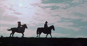 Movie still from “Alice's Restaurant” (1969), directed by Arthur Penn – A man riding on the back of a brown horse next to another man; Wide shot, Low angle