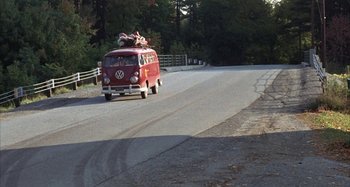 Movie still from “Alice's Restaurant” (1969), directed by Arthur Penn – A red van driving down a road with trees in the background; Wide shot, High angle