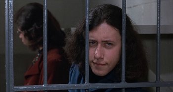 Movie still from “Alice's Restaurant” (1969), directed by Arthur Penn – A woman with long hair looking through a jail cell; Close Up shot, Low angle