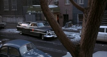 Movie still from “Alice's Restaurant” (1969), directed by Arthur Penn – An old car parked on the side of the street; Wide shot, High angle