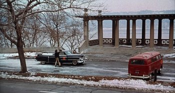 Movie still from “Alice's Restaurant” (1969), directed by Arthur Penn – A man standing next to a car on the side of a road; Extreme Wide shot, High angle
