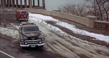 Movie still from “Alice's Restaurant” (1969), directed by Arthur Penn – A car driving down a road next to a body of water; Wide shot, High angle