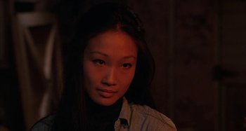 Movie still from “Alice's Restaurant” (1969), directed by Arthur Penn – A young woman with long black hair is posing for the camera; Close Up shot, Over the shoulder angle