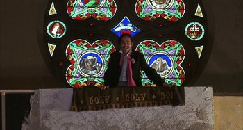 Movie still from “Alice's Restaurant” (1969), directed by Arthur Penn – A man standing in front of a stained glass window; Medium shot, Low angle