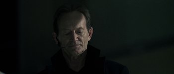 Movie still from “Alien vs. Predator” (2004), directed by Paul W.S. Anderson – An older man with his eyes closed and his head turned to the side; Close Up shot, Over the shoulder angle
