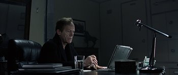 Movie still from “Alien vs. Predator” (2004), directed by Paul W.S. Anderson – An older man sitting in front of a laptop computer; Medium shot, Low angle