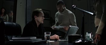 Movie still from “Alien vs. Predator” (2004), directed by Paul W.S. Anderson – Two men sitting in front of a laptop computer; Medium shot, Low angle