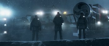 Movie still from “Alien vs. Predator” (2004), directed by Paul W.S. Anderson – Two men standing in the snow with headlights on; Wide shot, Low angle
